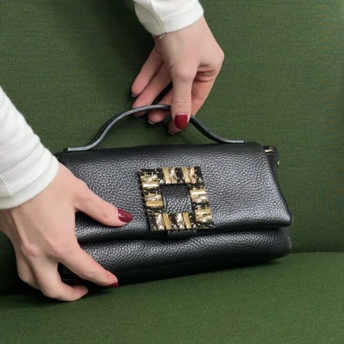 Pochette nera con fibbia gioiello su divano verde