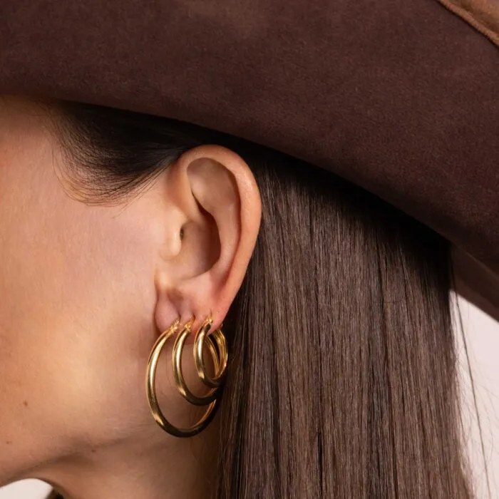 Dettaglio di orecchini dorati sotto un cappello